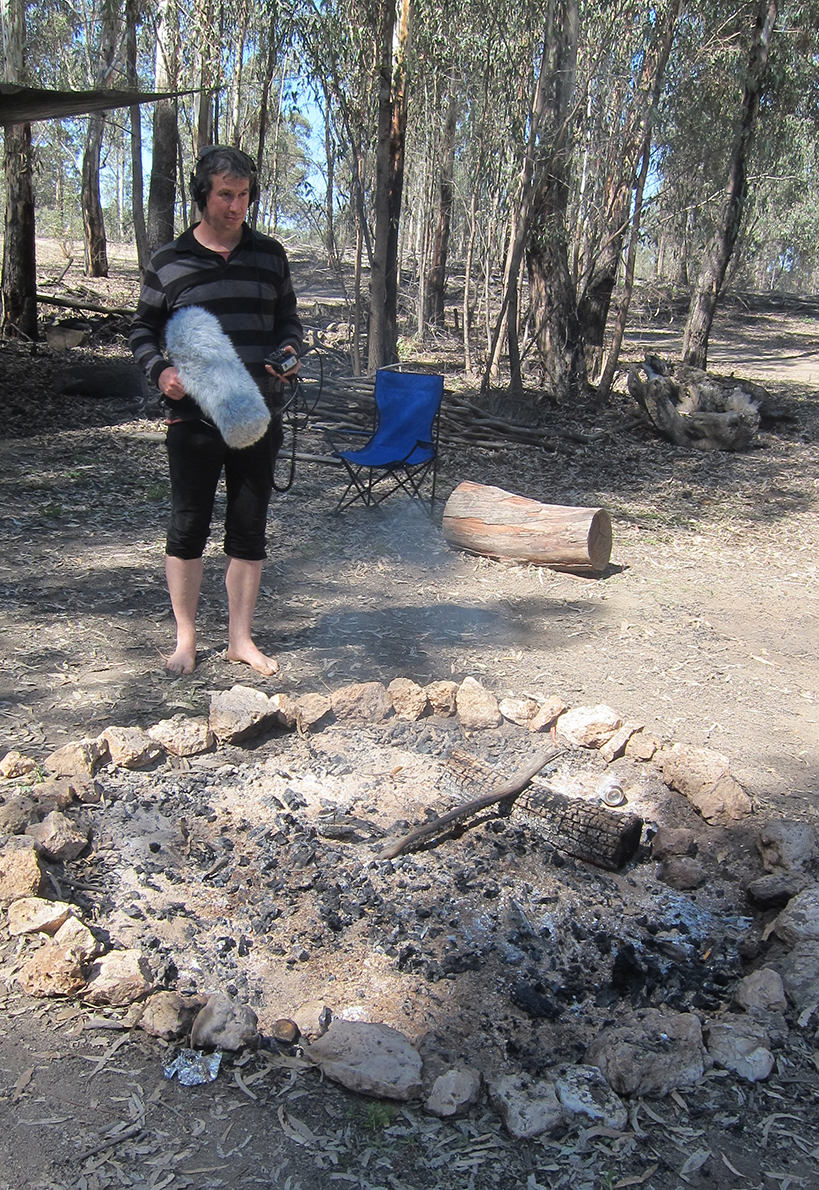 Jordan Lacey – Field Recording (Interpretive Wonderings Workshop). A man (Jordan Lacey) recording a fire with a microphone.