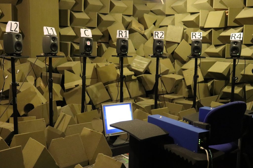 Image shows a chair with a bank of speakers lined up with labels on them