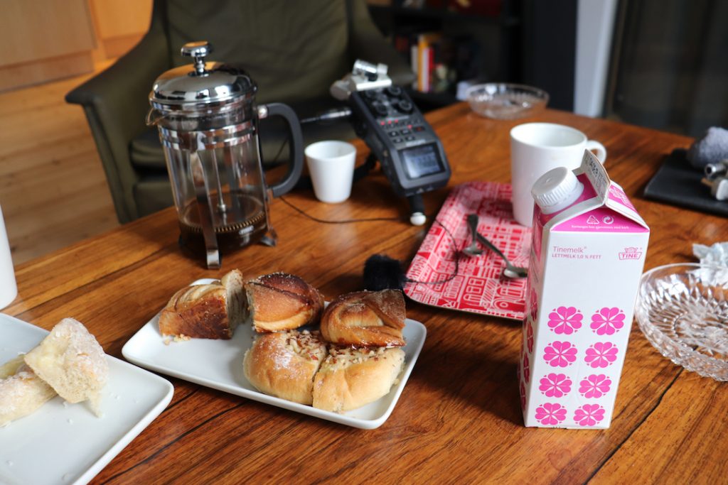 Image shows a table with a handheld recording device on it along with coffee and cake